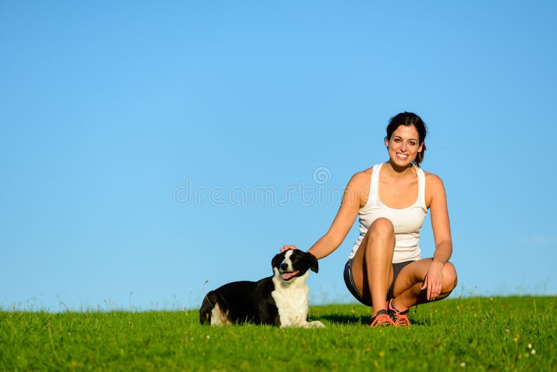 Mujer deportiva feliz que toma un resto de ejercicio con su perro foto de archivo libre de regalías Mujer deportiva feliz que toma un resto de ejercicio con su perro foto de archivo libre de regalías