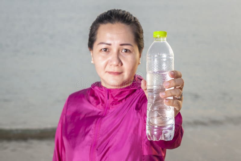 Mujer deportiva que ofrece una botella de agua, forma de vida sana imágenes de archivo libres de regalías Mujer deportiva que ofrece una botella de agua, forma de vida sana imágenes de archivo libres de regalías