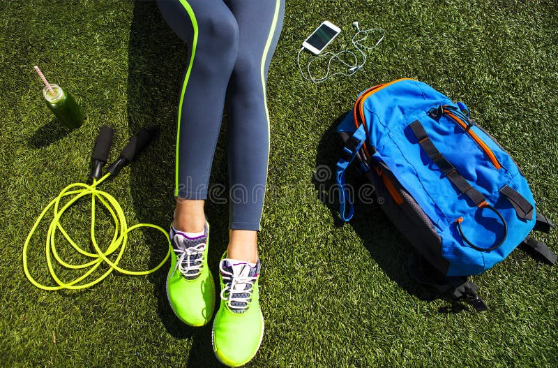 Mujer deportiva que se sienta en la hierba verde foto de archivo libre de regalías Mujer deportiva que se sienta en la hierba verde foto de archivo libre de regalías