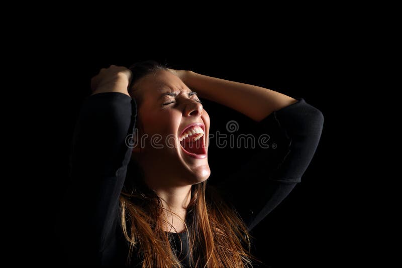 Depressed woman crying and shouting desperately isolated in a black background. Depressed woman crying and shouting desperately isolated in a black background