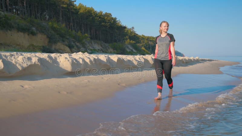 Mujer descalza caminando por la playa