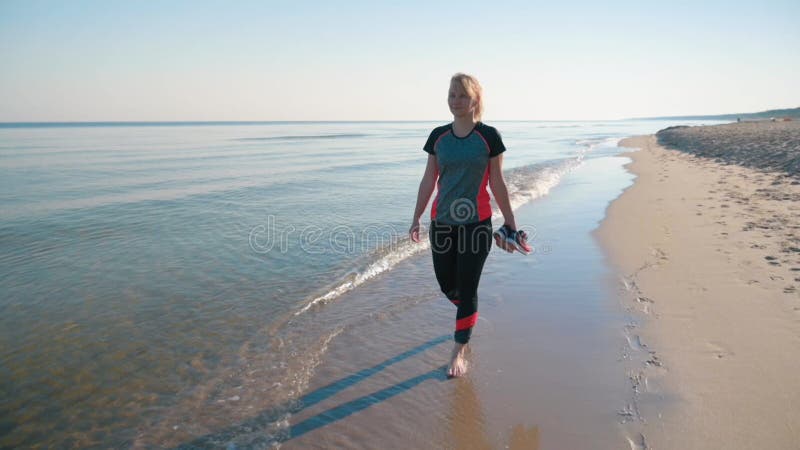 Mujer descalza caminando por la playa