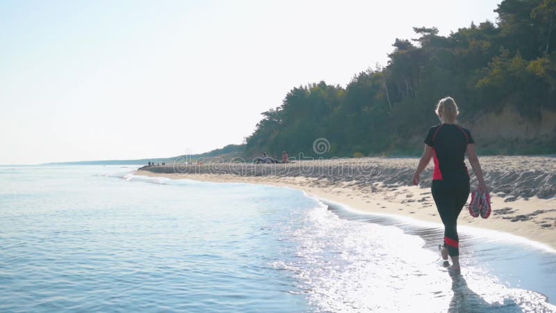 Mujer descalza caminando por la playa