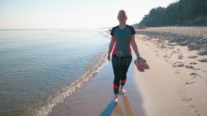 Mujer descalza caminando por la playa