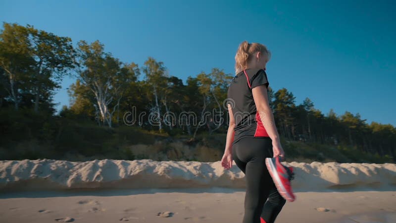 Mujer descalza caminando por la playa