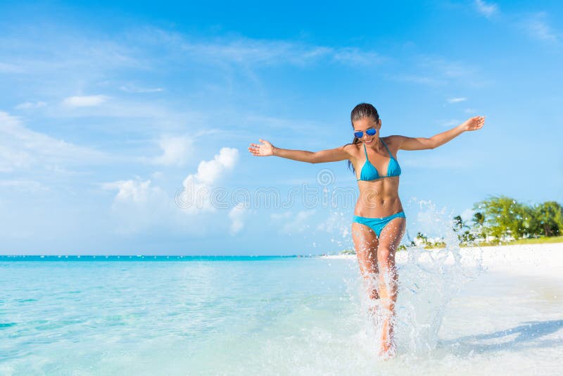 Mujer despreocupada de las vacaciones de la diversión de la playa que salpica el agua