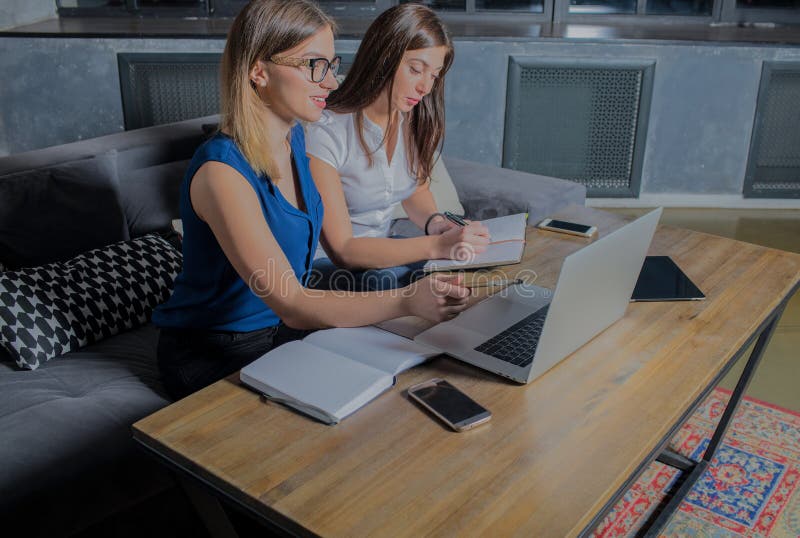 Mujer dos que trabaja junto en oficina con el ordenador portátil, escribiendo a un notario foto de archivo libre de regalías Mujer dos que trabaja junto en oficina con el ordenador portátil, escribiendo a un notario foto de archivo libre de regalías