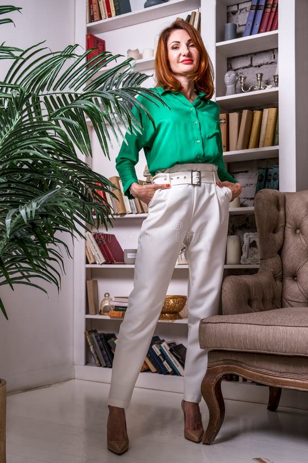 Mujer Elegante Con Pantalones Blancos Blusa Verde Se Alza Contra El Fondo De Una Librería En Su Oficina Imagen de archivo - Imagen de empleado, 225667317