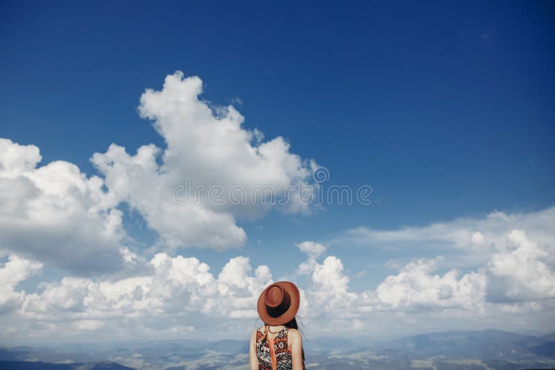 Mujer elegante del viajero en el sombrero que mira el cielo y las montañas caderas imagen de archivo libre de regalías Mujer elegante del viajero en el sombrero que mira el cielo y las montañas caderas imagen de archivo libre de regalías