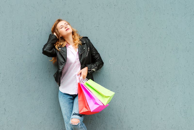 Mujer elegante feliz con los bolsos de compras sobre fondo gris Mujer joven bonita que goza en compras Consumerismo, compras, ven foto de archivo
