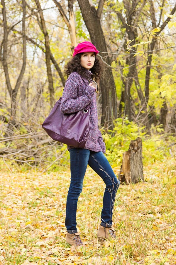 Mujer elegante joven con un bolso grande en el parque del otoño foto de archivo Mujer elegante joven con un bolso grande en el parque del otoño foto de archivo