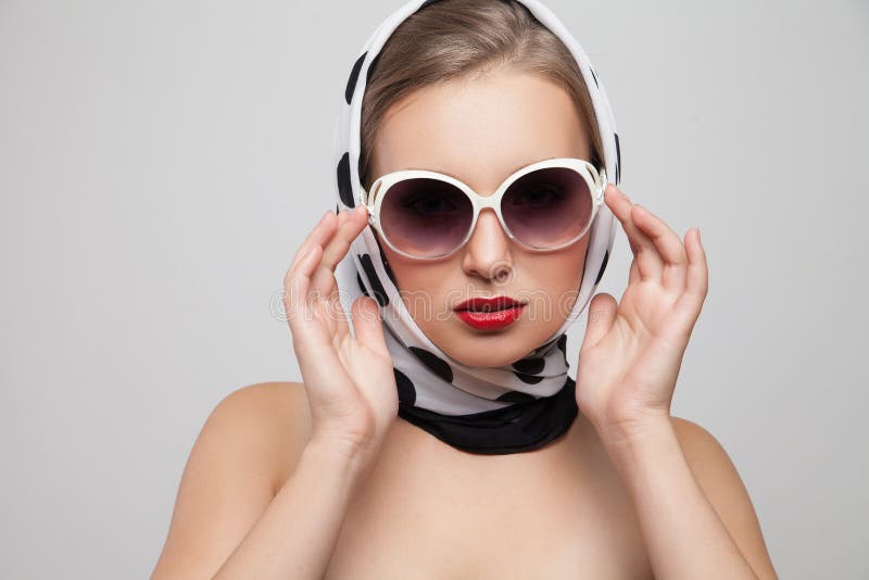Mujer elegante que presenta en gafas de sol y bufanda encendido foto de archivo libre de regalías Mujer elegante que presenta en gafas de sol y bufanda encendido foto de archivo libre de regalías