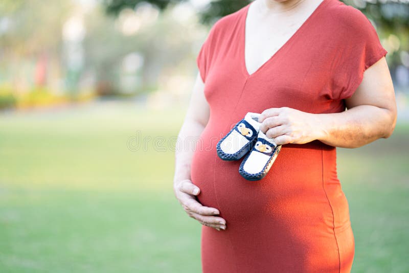 Mucho Saludo cinta Mujer Embarazada Con Ropas De Maternidad Rojas Sosteniendo Zapatos De Bebé  Bonitos En Su Bebé Imagen de archivo - Imagen de embarazo, abdomen:  171747755