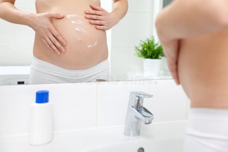 Mujer embarazada en espejo del cuarto de baño foto de archivo Mujer embarazada en espejo del cuarto de baño foto de archivo