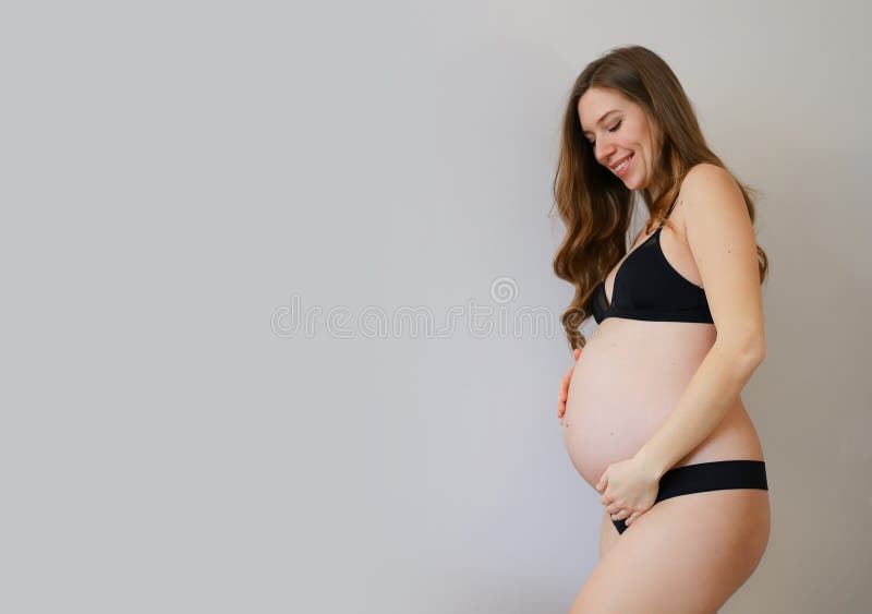 Embarazada En Ropa Interior Negra Sosteniendo Su Vientre En Fondo De Gris. Imagen de archivo Imagen expectativa, actitud: 195138823