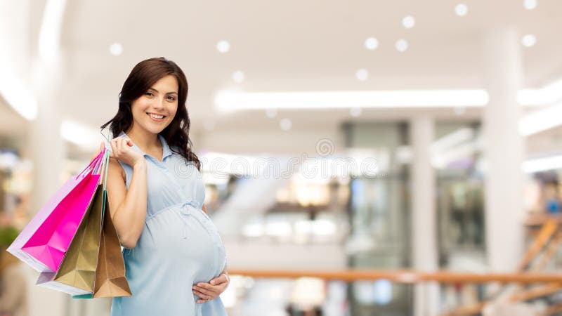 Mujer embarazada feliz con los bolsos de compras imagen de archivo libre de regalías Mujer embarazada feliz con los bolsos de compras imagen de archivo libre de regalías