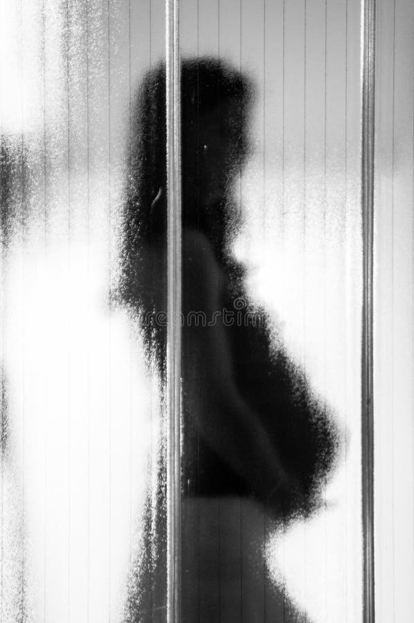 Mujer embarazada joven detrás del vidrio mate con la atmósfera cambiante oscura, símbolo de la depresión postparto fotografía de archivo libre de regalías Mujer embarazada joven detrás del vidrio mate con la atmósfera cambiante oscura, símbolo de la depresión postparto fotografía de archivo libre de regalías