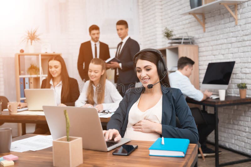 Mujer embarazada linda que habla en las auriculares en oficina Empresaria embarazada en oficina fotografía de archivo libre de regalías Mujer embarazada linda que habla en las auriculares en oficina Empresaria embarazada en oficina fotografía de archivo libre de regalías