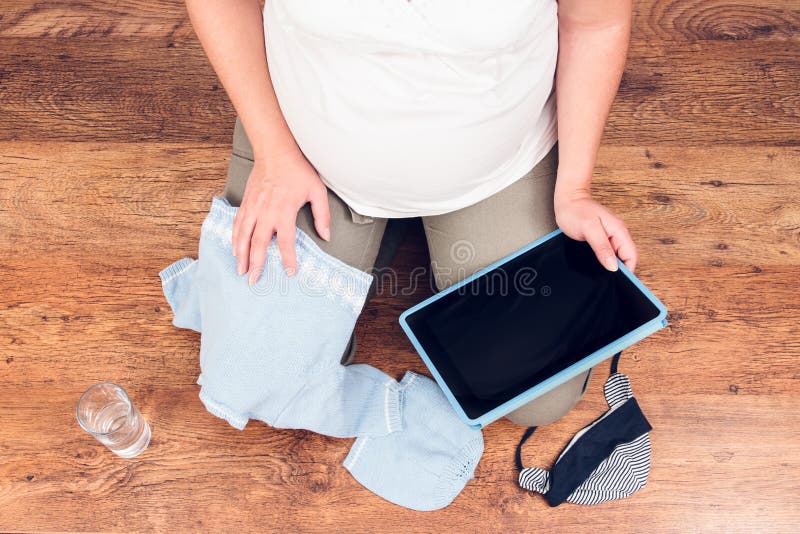 Pregnant woman doing online shopping on a tablet for expected baby. Pregnant woman doing online shopping on a tablet for expected baby