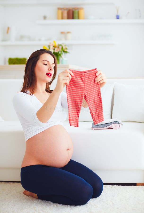 Mujer Embarazada Que Prepara La Ropa Para Su Nuevo Bebé En Casa Imagen de - Imagen de hembra, espere: 86477235