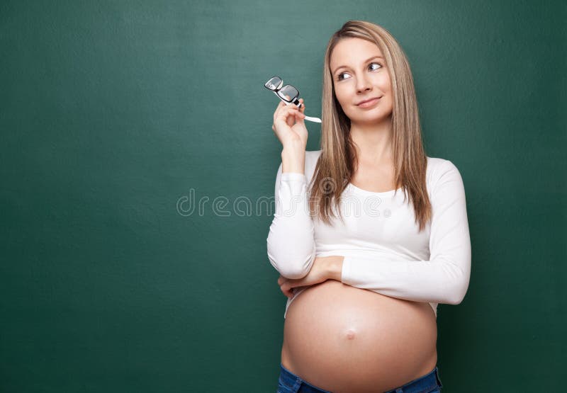 Mujer embarazada y una pizarra con el copyspace foto de archivo Mujer embarazada y una pizarra con el copyspace foto de archivo