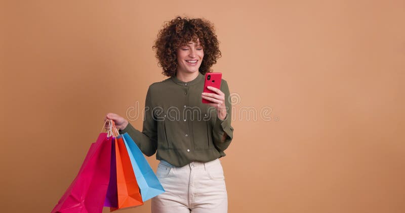 Mujer emocionada con bolsas de compras y teléfonos celulares en el estudio almacen de video