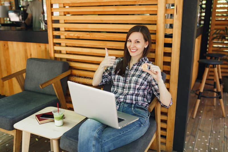 Mujer en el café de la cafetería de la calle del aire libre que se sienta con el ordenador de la PC del ordenador portátil, bitco fotos de archivo