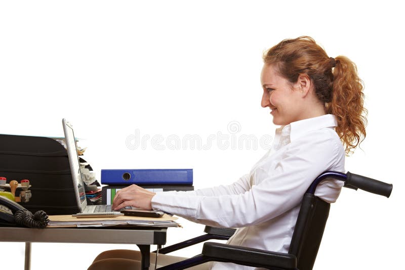 Mujer en el sillón de ruedas que trabaja en el escritorio fotografía de archivo Mujer en el sillón de ruedas que trabaja en el escritorio fotografía de archivo