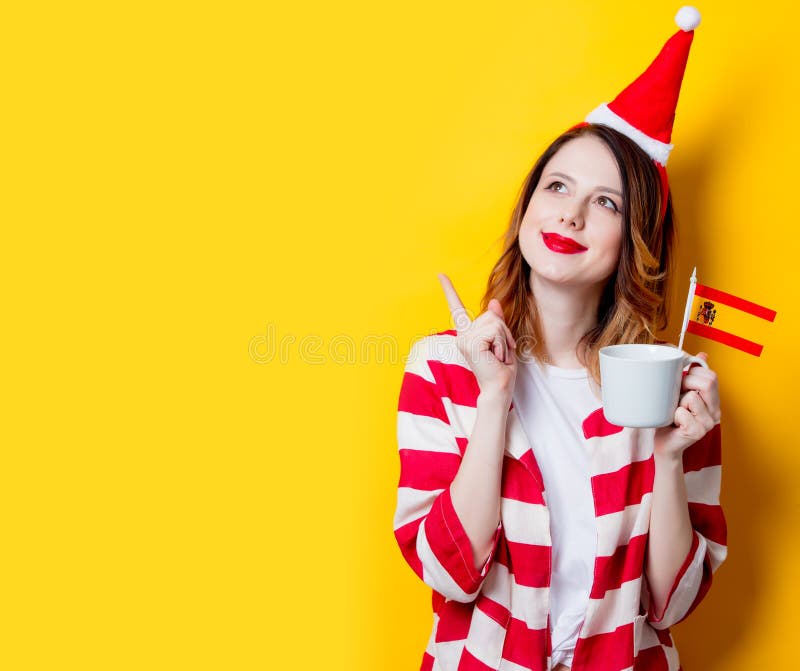 Mujer en el sombrero de Santa Claus con la bandera y la taza de España fotografía de archivo Mujer en el sombrero de Santa Claus con la bandera y la taza de España fotografía de archivo