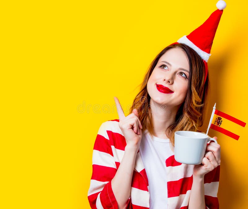 Mujer en el sombrero de Santa Claus con la bandera y la taza de España foto de archivo Mujer en el sombrero de Santa Claus con la bandera y la taza de España foto de archivo