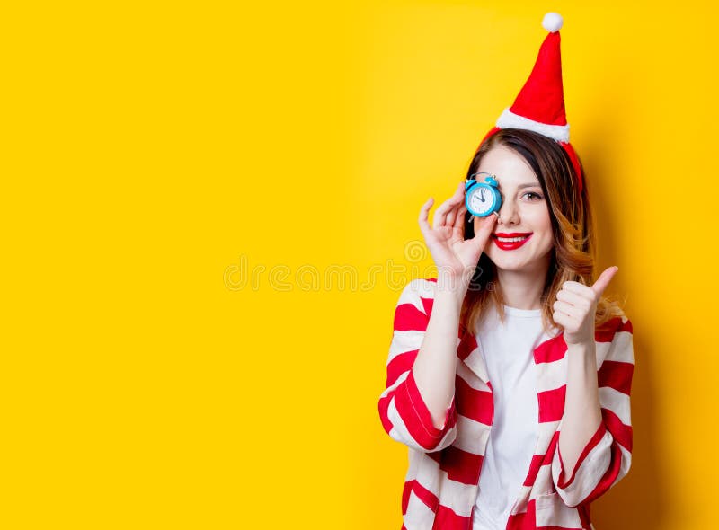 Mujer en el sombrero de Santa Claus con poco despertador imagen de archivo Mujer en el sombrero de Santa Claus con poco despertador imagen de archivo