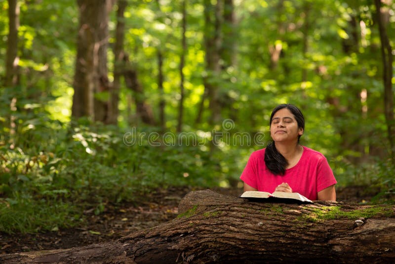 Mujer en Forest Preserve con la biblia que se arrodilla en rezo