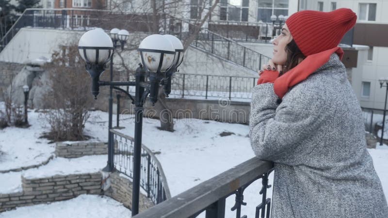 Mujer en la capa que se inclina en la verja