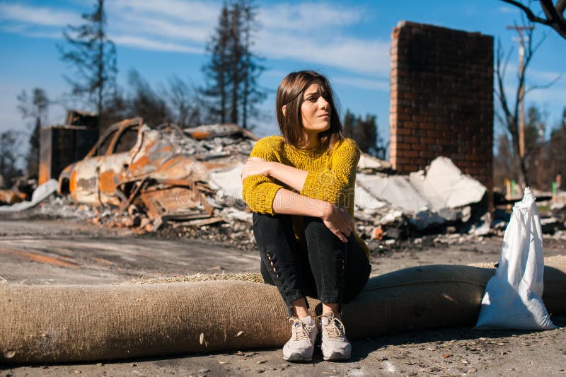 Mujer en la casa y la yarda arruinadas quemadas, después del desastre del fuego