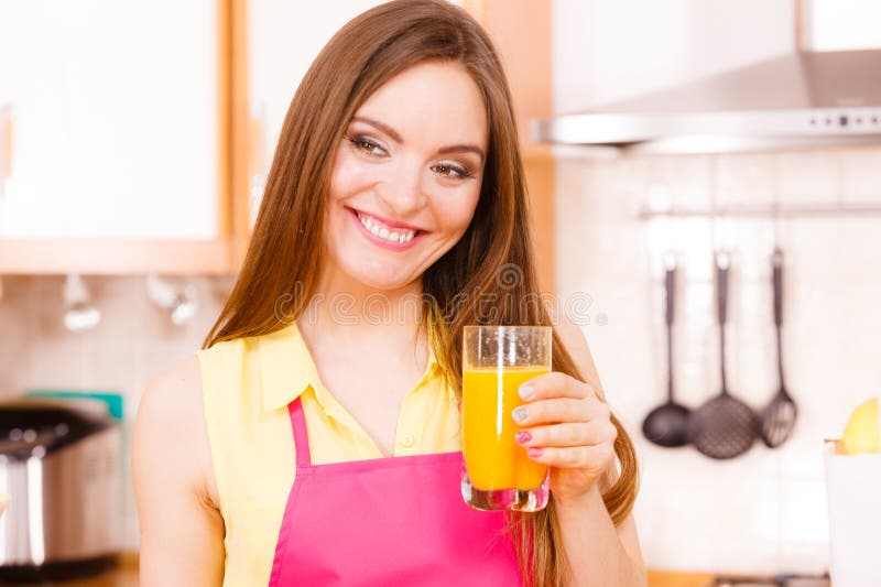 Mujer en la cocina tomando zumo de naranja natural fotos de archivo libres de regalías