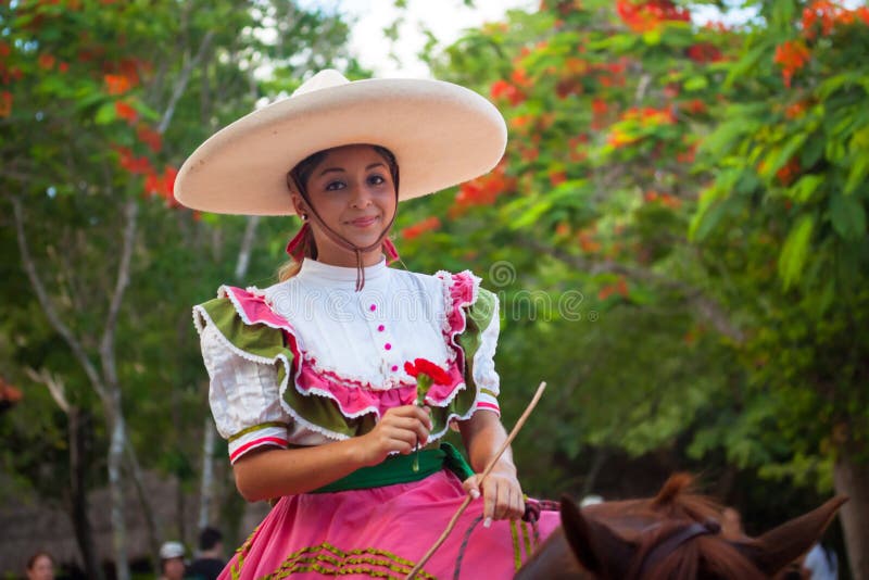 Xcaret, Mexico - July 19, 2011: Woman at traditional Mexican Fiesta Charra Show in Xcaret Park with charros display their acrobatic skills on horseback. Xcaret, Mexico - July 19, 2011: Woman at traditional Mexican Fiesta Charra Show in Xcaret Park with charros display their acrobatic skills on horseback