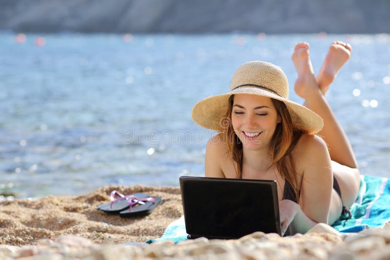 Mujer en la playa que hojea medios sociales en un ordenador en verano Mujer en la playa que hojea medios sociales en un ordenador en verano