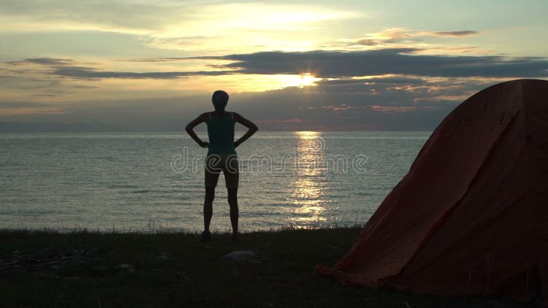 Mujer en la salida del sol de mirada que acampa por la mañana