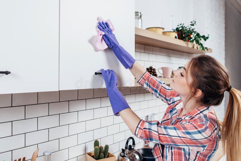 Mujer en los guantes de goma que limpian al armario de cocina fotografía de archivo libre de regalías Mujer en los guantes de goma que limpian al armario de cocina fotografía de archivo libre de regalías