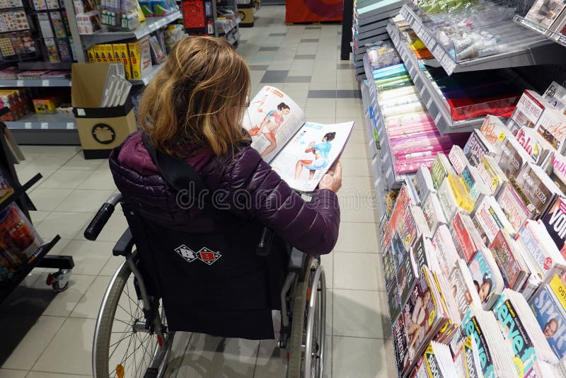 Mujer en silla de ruedas en la tienda leyendo una revista de fitness fotografía de archivo Mujer en silla de ruedas en la tienda leyendo una revista de fitness fotografía de archivo