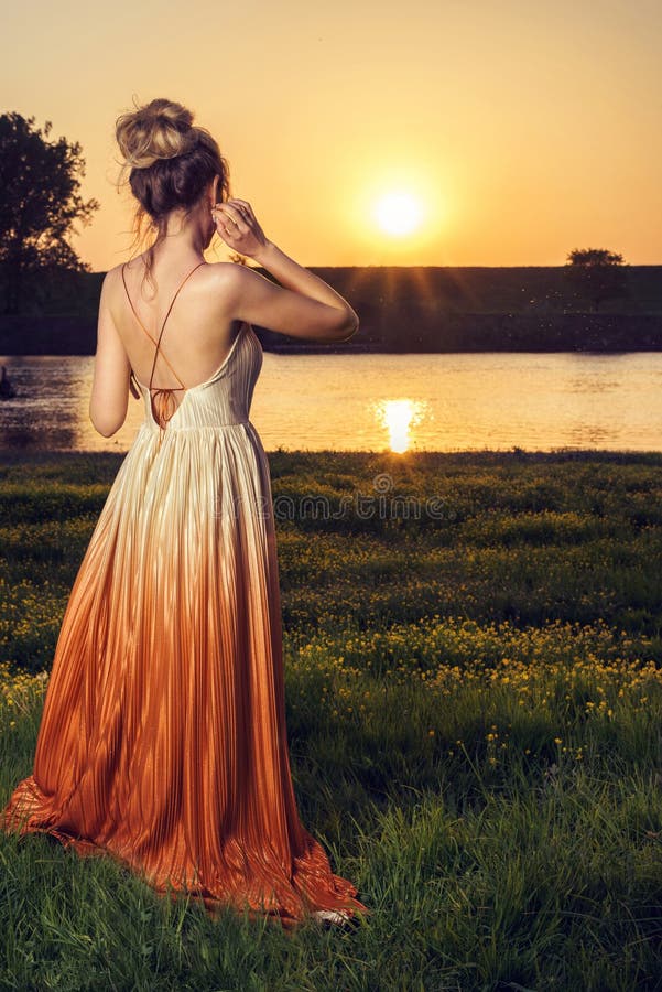 Mujer en un vestido atractivo largo en la puesta del sol Opinión hermosa del paisaje, tiro de la parte posterior foto de archivo libre de regalías Mujer en un vestido atractivo largo en la puesta del sol Opinión hermosa del paisaje, tiro de la parte posterior foto de archivo libre de regalías