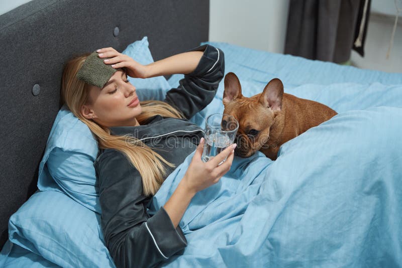 Mujer enferma y su perrito francés en la cámara de noche fotos de archivo
