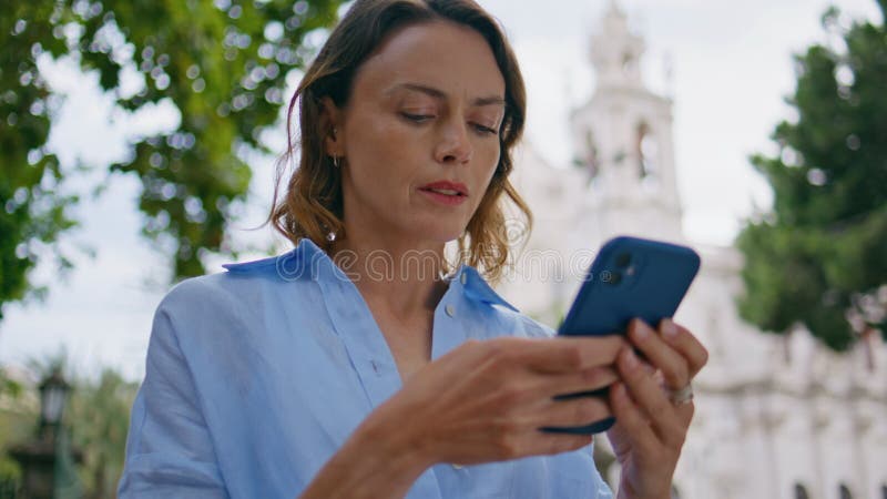 Mujer enfocada a chatear smartphone en el cierre de los parques de verano. Señora amiga fotos de archivo libres de regalías