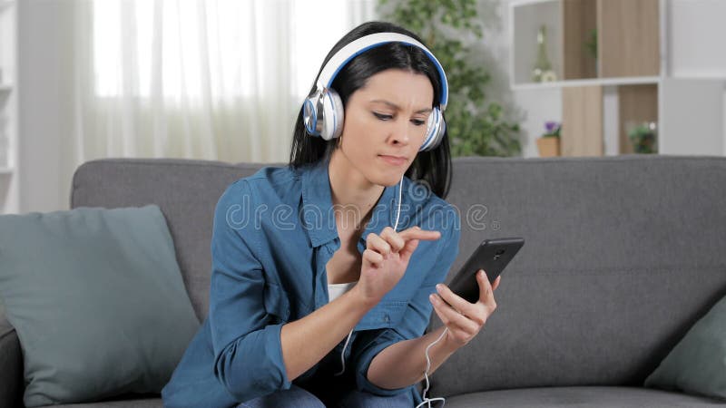 Mujer enojada que escucha la música usando el teléfono estrellado