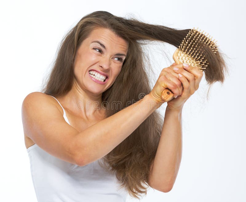 Angry woman having hard time combing hair isolated on white. Angry woman having hard time combing hair isolated on white