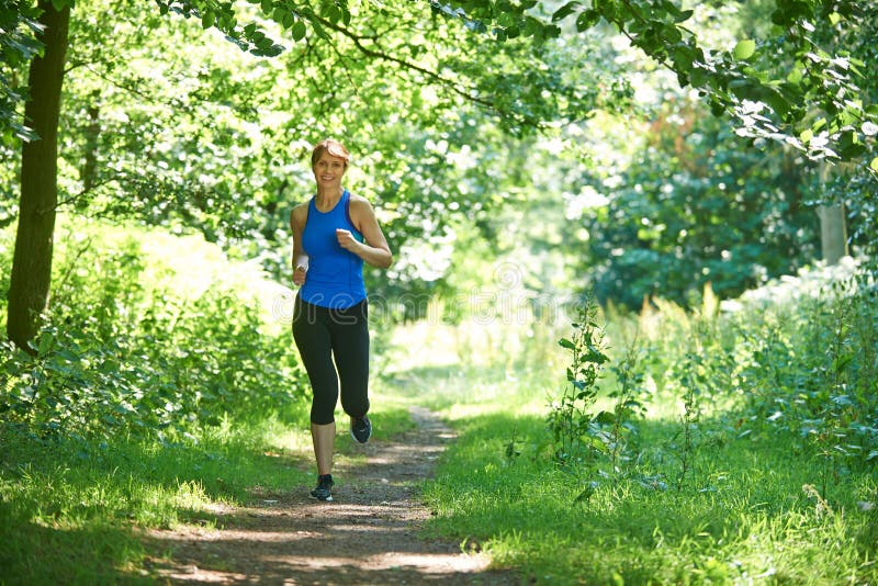 Mujer envejecida centro que corre en campo foto de archivo libre de regalías Mujer envejecida centro que corre en campo foto de archivo libre de regalías