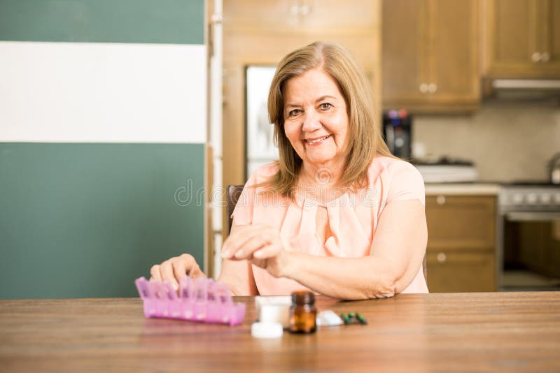 Mujer envejecida feliz que llena su caja de la píldora imagen de archivo Mujer envejecida feliz que llena su caja de la píldora imagen de archivo