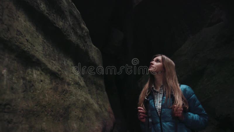 Mujer europea atractiva, turista con una mochila que camina en la cueva oscura, haciendo girar dentro de ella, observación