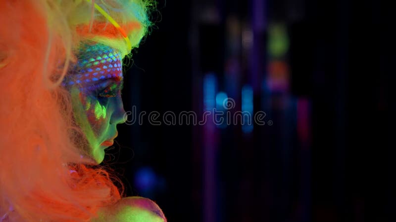 Mujer Excéntrica Con Pintura Fluorescente En La Cara Y El Cuerpo En La  Discoteca Retrato Lateral En La Oscuridad Almacen De Video - Vídeo de club,  disco: 220867497