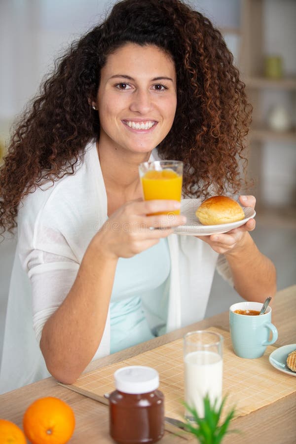 Mujer feliz con el pelo castaño desayunando foto de archivo libre de regalías